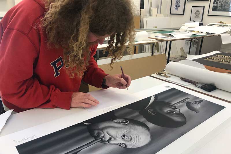 Owen Dippie signing a large portrait print in the studio
